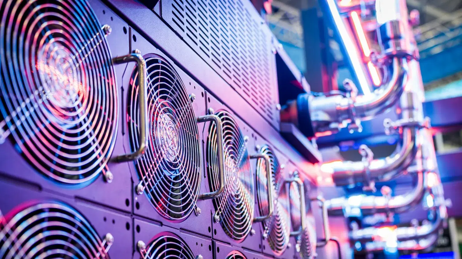 Rows of cooling fans and coolant pipework on a server rack, lit magenta and blue.