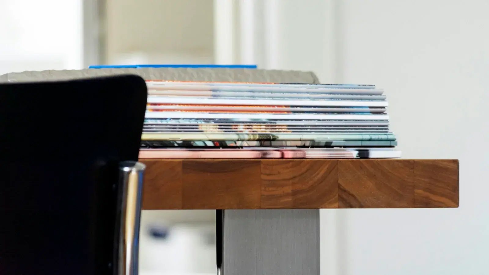 A stack of books and bound documents on a wooden table.