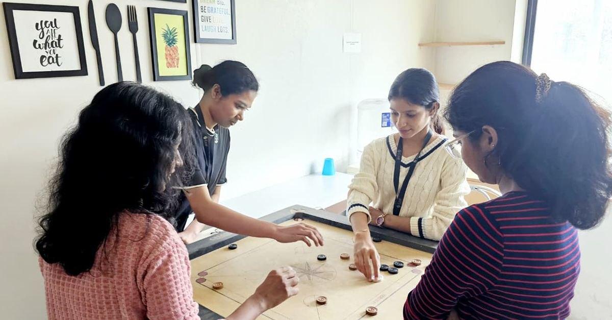 Colleagues playing carrom on a board in the iLeaf office