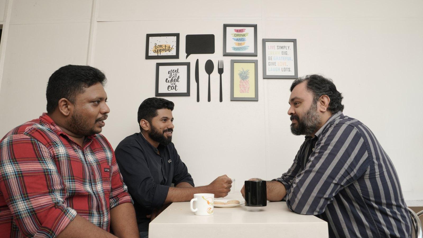 Three colleagues talking over coffee at the pantry table in the iLeaf office